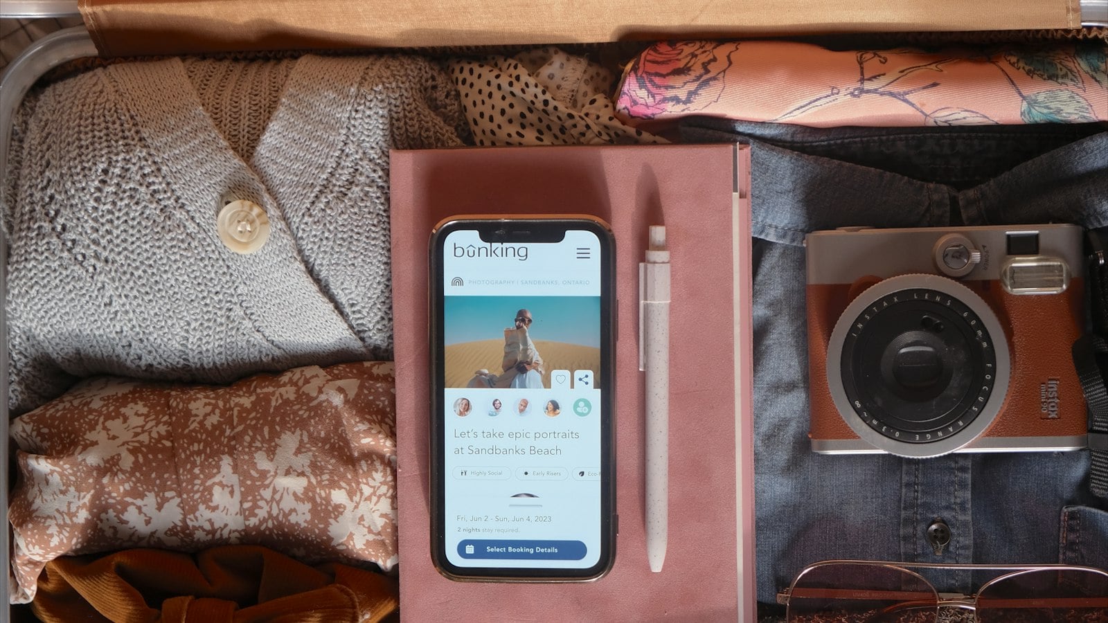 An open packed suitcase with a phone and camera on top (photo: Paige Cody / Unsplash)