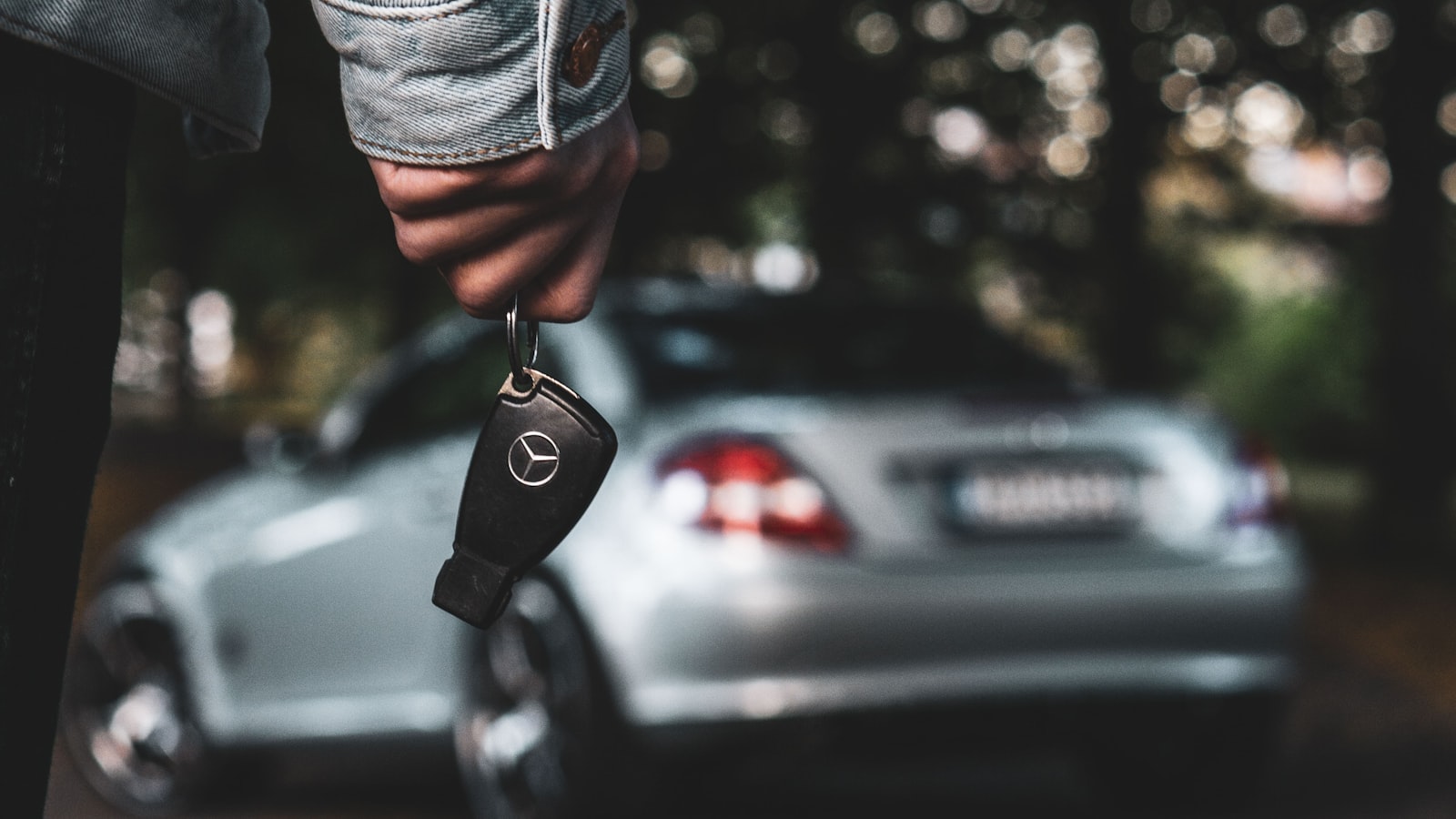 A person holding a car key beside a silver car (photo: Janne Aspegren / Unsplash)