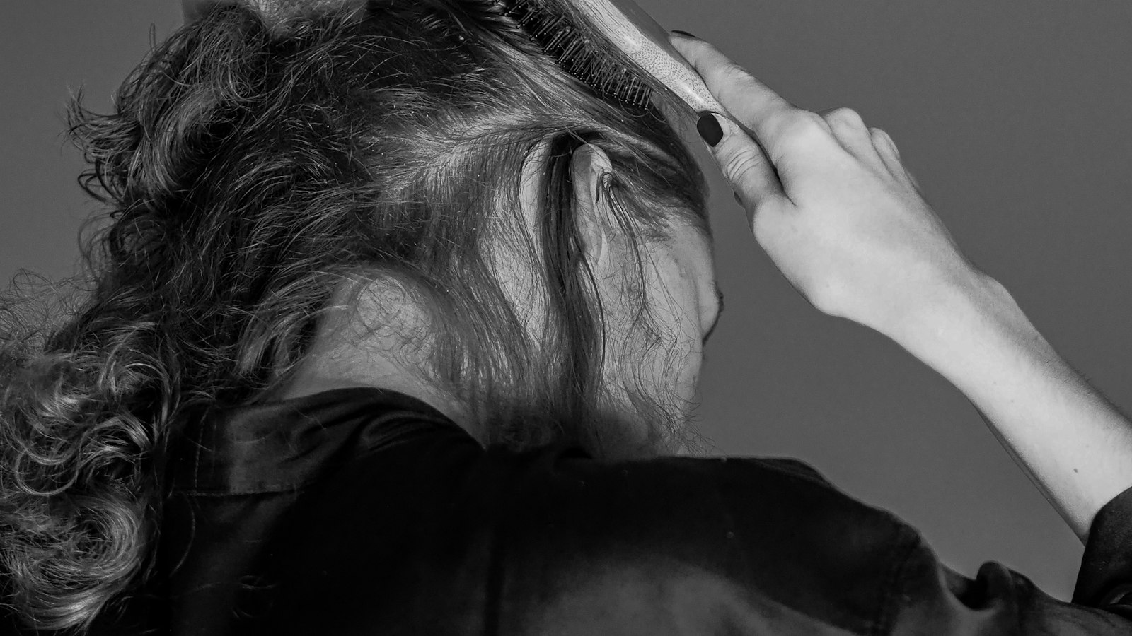 Person working through curly hair with a styling tool (photo: Laura Chouette / Unsplash)