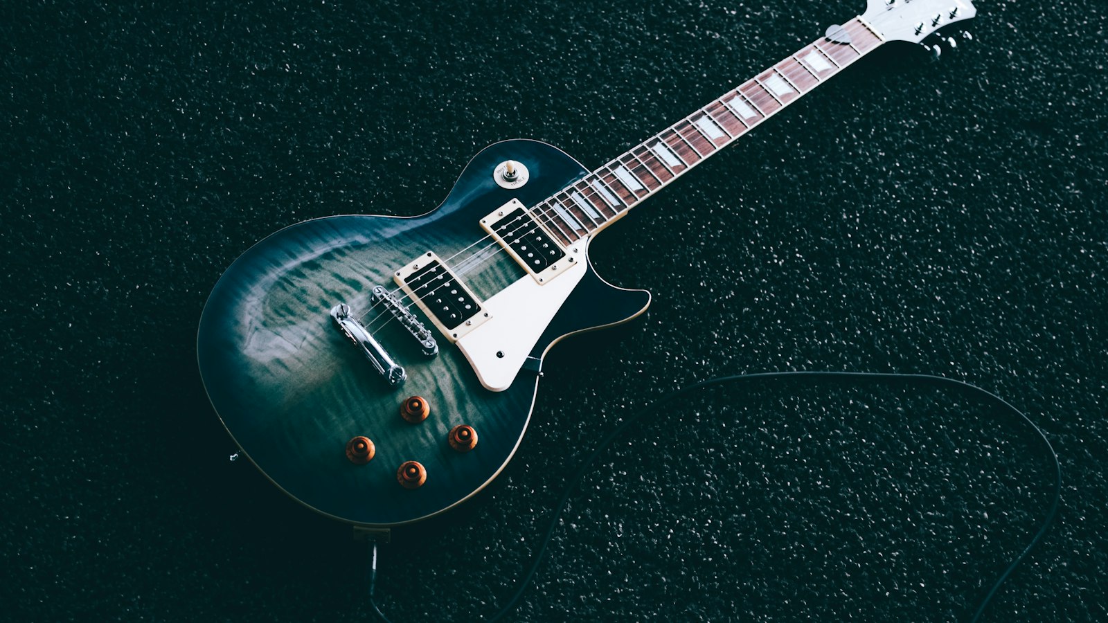 Electric guitar laid on a dark surface (photo: Jeremy Allouche / Unsplash)