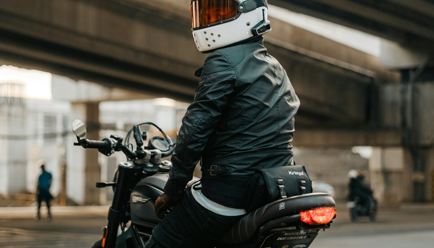 A motorcyclist seen from behind wearing a textile riding jacket, gloves and a full-face helmet (photo: Kristian Angelo / Unsplash)