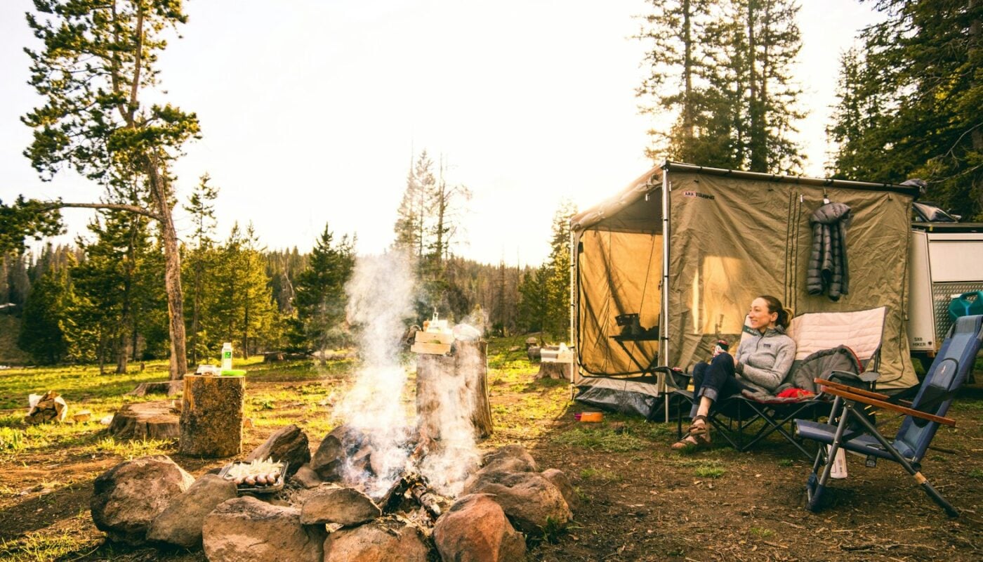 Campsite with a tent, camp chair and fire in the woods (photo: Chris Holder / Unsplash)