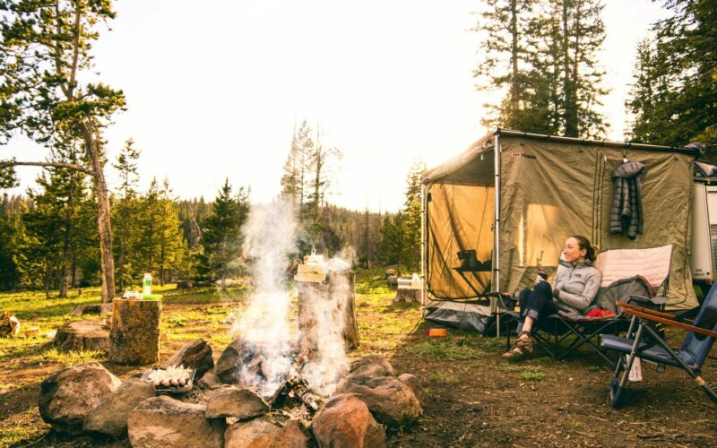 Campsite with a tent, camp chair and fire in the woods (photo: Chris Holder / Unsplash)