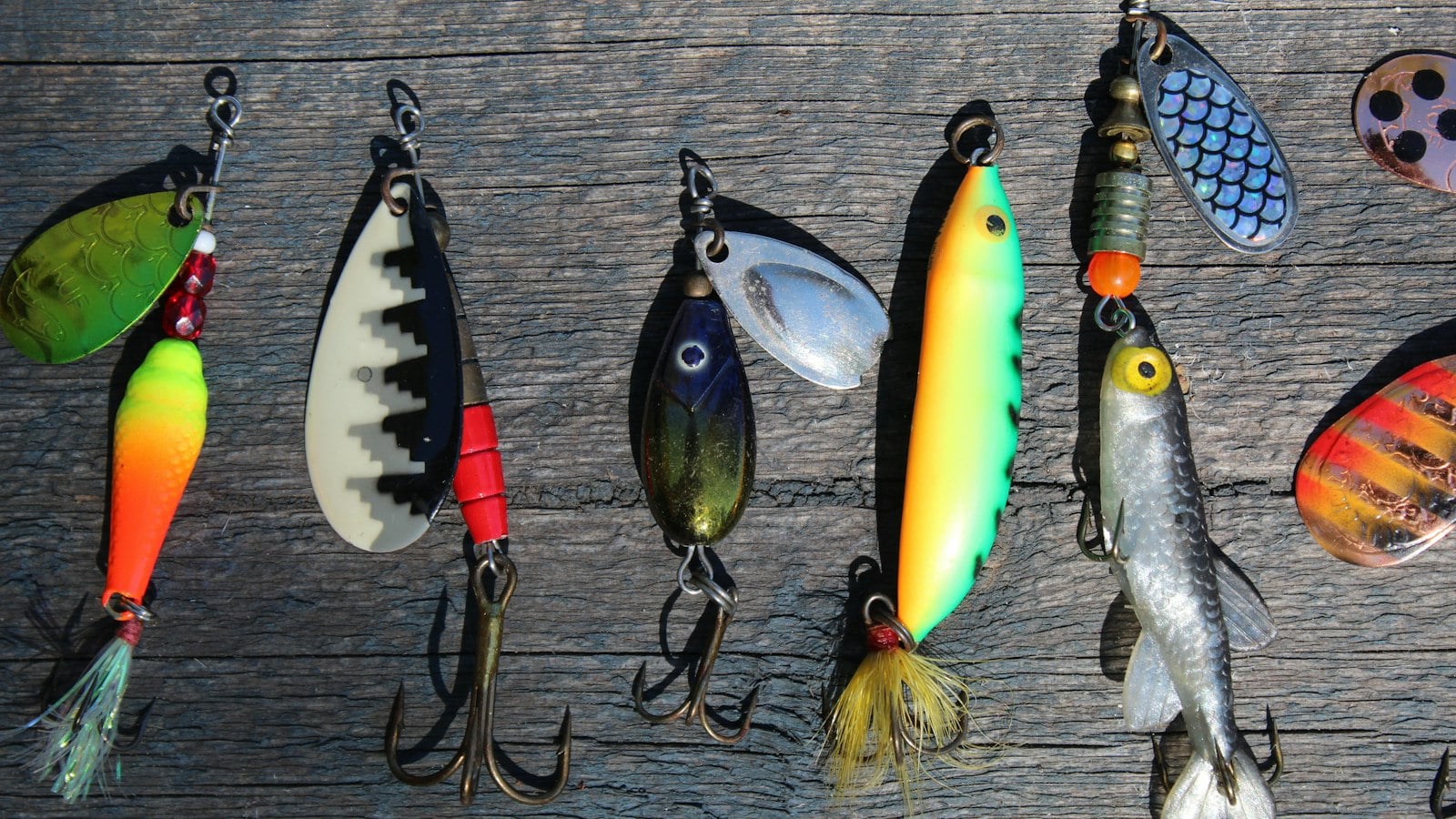 Colourful fishing lures laid out on wood (photo: Anne Nygård / Unsplash)