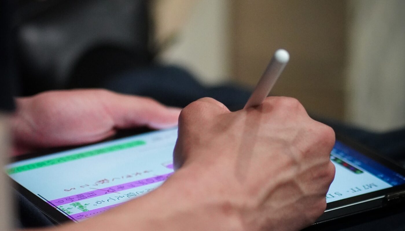 A person using a stylus to sign a document on a tablet screen (photo: Yosuke Ota / Unsplash)