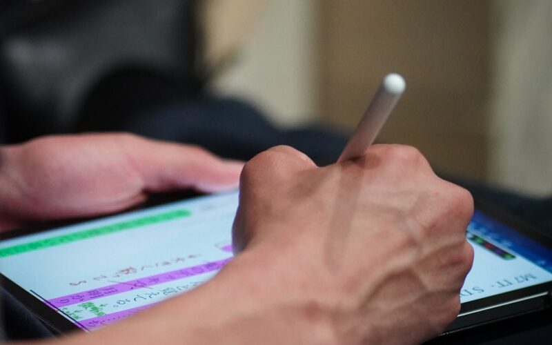A person using a stylus to sign a document on a tablet screen (photo: Yosuke Ota / Unsplash)