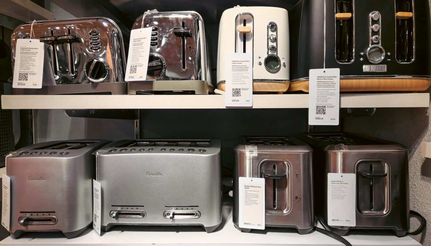 Toasters lined up on a shop shelf with printed specification cards beside each one (photo: Zoshua Colah / Unsplash)