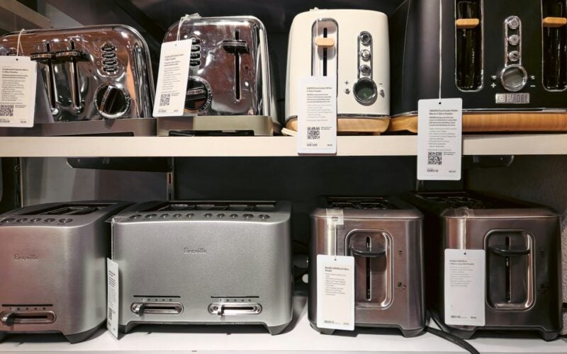 Toasters lined up on a shop shelf with printed specification cards beside each one (photo: Zoshua Colah / Unsplash)