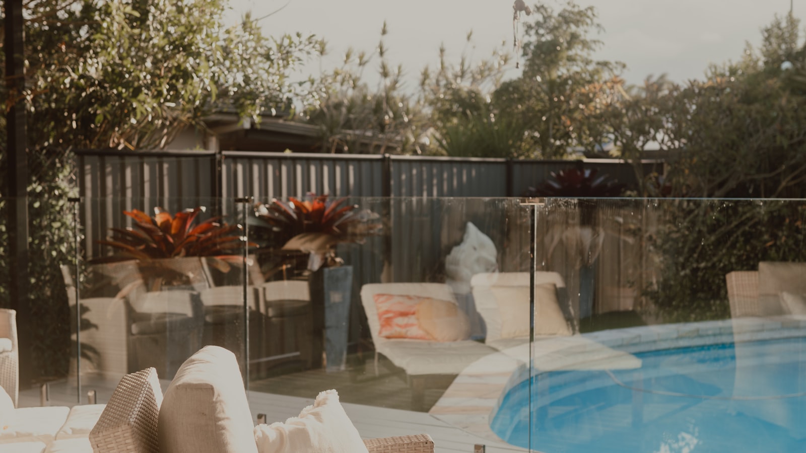 A sunny patio with wicker chairs beside a private swimming pool (photo: Grace Anne Bobadilla / Unsplash)