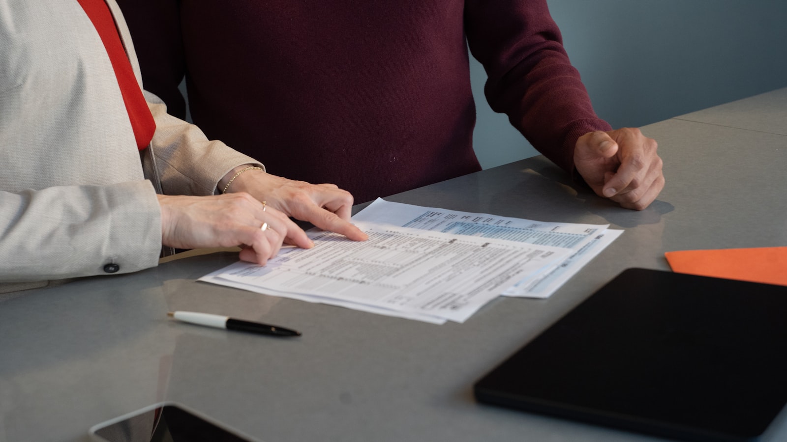 Two people working through printed documents at a table (photo: Olena Kholina / Unsplash)