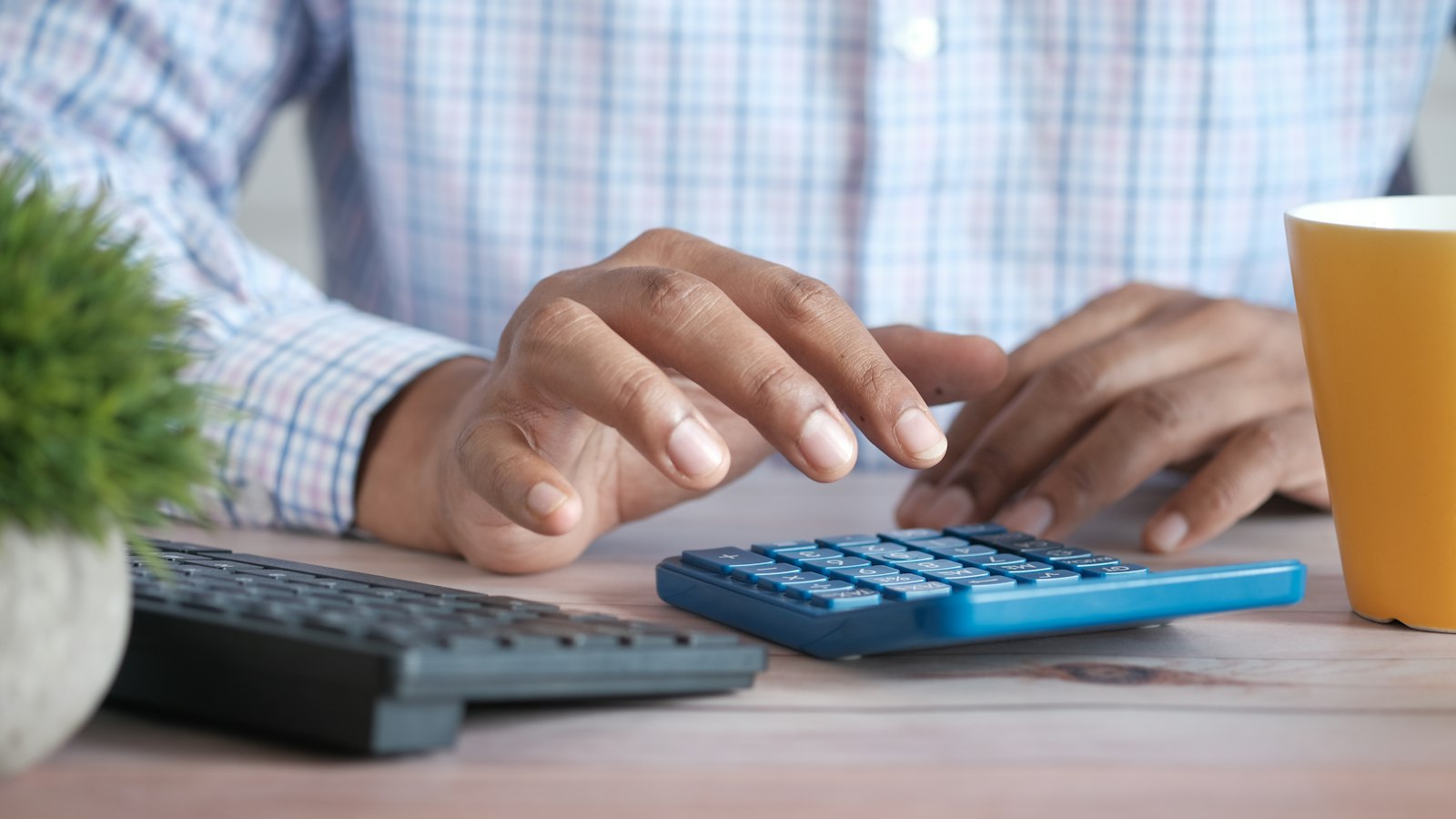 Hands using a calculator at a desk (photo: Towfiqu barbhuiya / Unsplash)