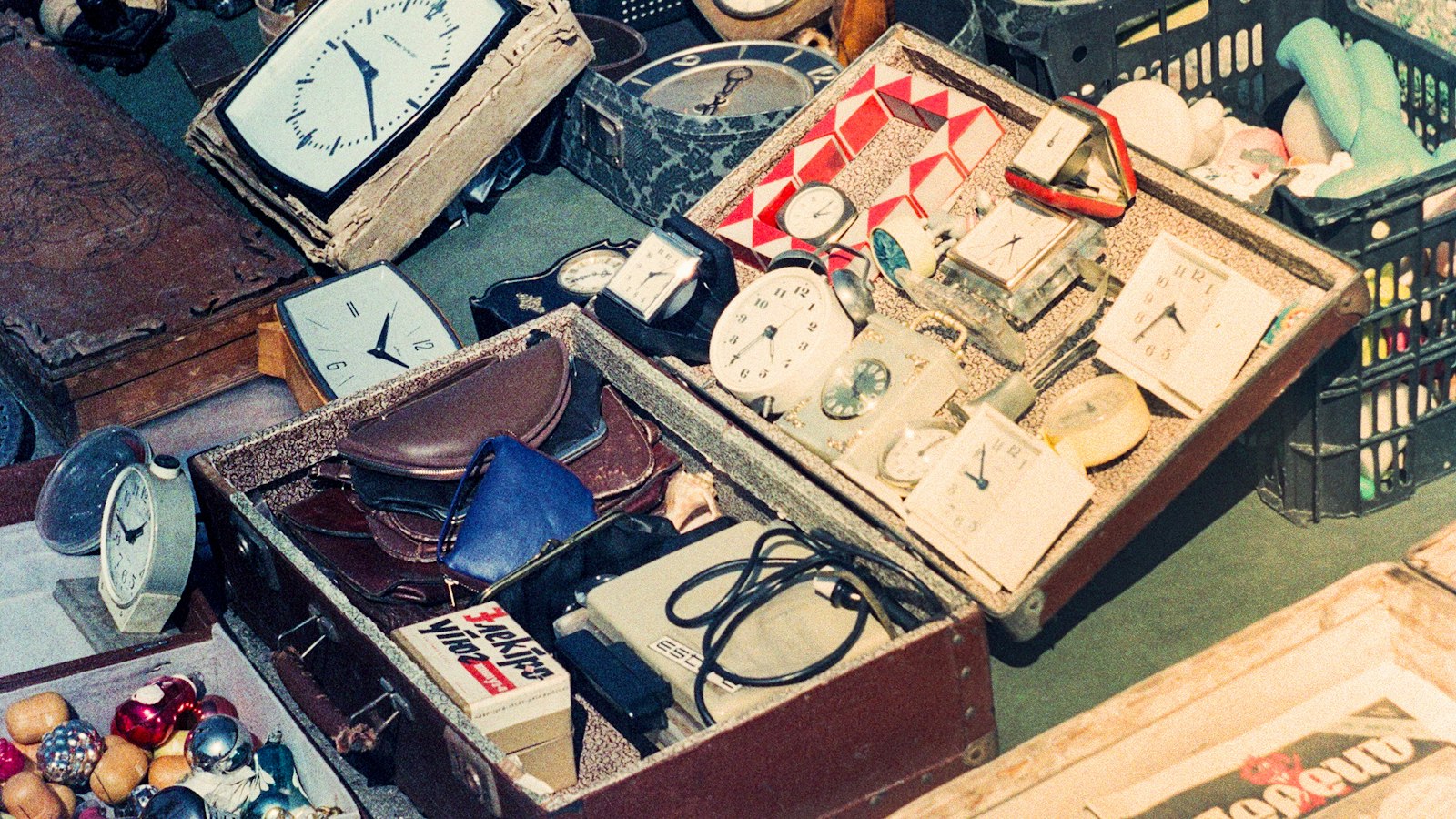 Trays of old clocks, watch faces and loose parts laid out on a flea-market stall