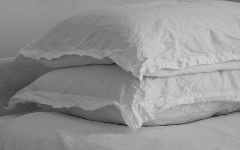 Two white pillows stacked on a made bed (photo: the blowup / Unsplash)