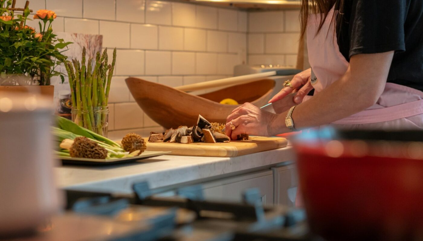 Woman chopping fresh vegetables on a board in a kitchen (photo: Douglas Fehr / Unsplash)