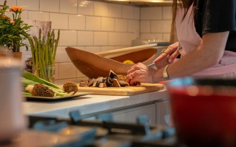 Woman chopping fresh vegetables on a board in a kitchen (photo: Douglas Fehr / Unsplash)