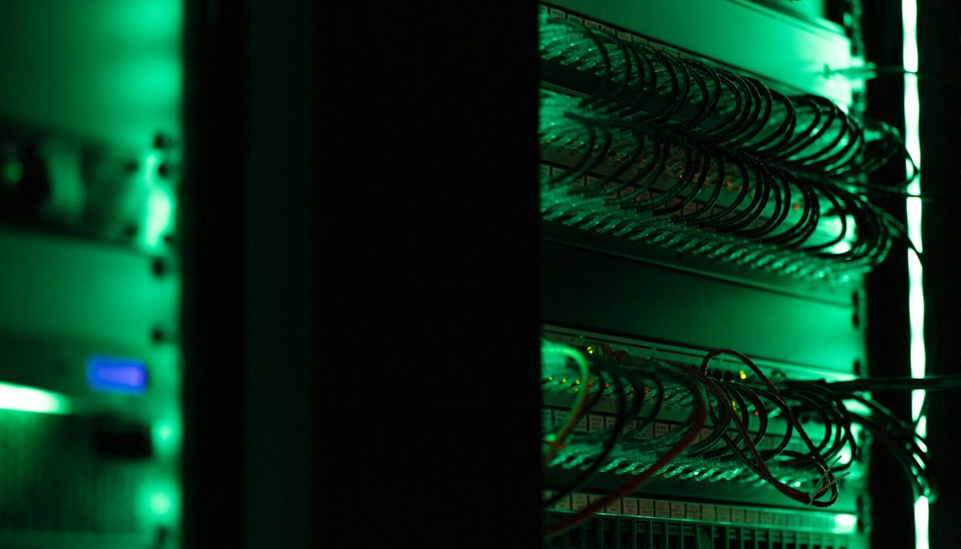 Rack of servers lit green in a data centre (photo: Tyler / Unsplash)