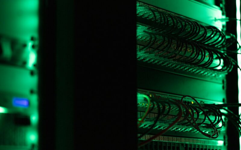 Rack of servers lit green in a data centre (photo: Tyler / Unsplash)